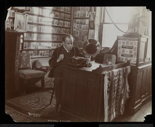 Marshall P. Wilder hört in seinem Büro eine Schallplatte auf einem Victrola, 1898-99